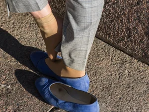 Feet in transparent short socks and flats closeups on the street: candid girl taking off her shoe and plating with her foot in public