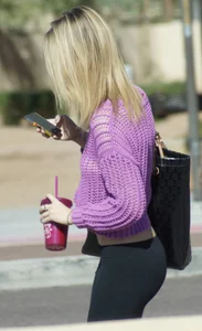 Beautiful skinny blonde in tight leggings and purple crop top showing sexy stomach
