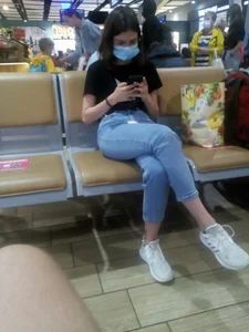 Cute Girl in a Medical Mask Sitting Cross-Legged in Blue Jeans Candid Photo