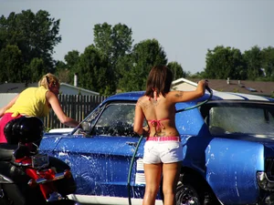 Group of cute girls at a car wash in bikinis and shorts