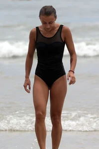 Skinny sexy lady on the beach in a black swimsuit