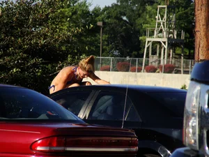 Group of cute girls at a car wash in bikinis and shorts