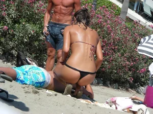 Sexy girl on the beach getting some sun in a little black thong bikini