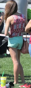 Brunette skinny teen in green shorts playing in a bounce house