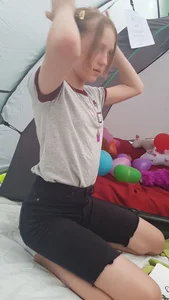 Young Skinny Girl in Tight Denim Shorts Sitting on Her Knees in a Tent