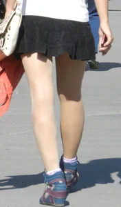 Girl in a Short Skirt and Pantyhose Walking Down the City Street
