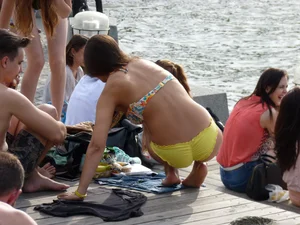 Cute Girl in Denim Shorts and Swimsuit Undressing on the Riverbank Candid Photo
