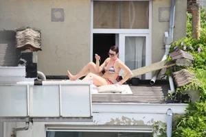 Neighbor on rooftop tanning in bikinis