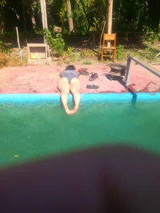 Chubby Girl in a One-Piece Swimsuit Lying by the Pool With Her Feed in Water