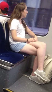 Cute Girl in Denim Shorts Sitting in Public Train With Crossed Legs
