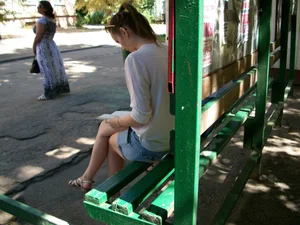 Hot Girl in Sandals Reading on a Bus Stop with Her Legs Crossed