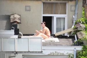 Neighbor on rooftop tanning in bikinis