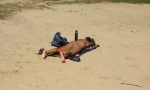 Sexy girl getting some sun laying on the beach in thong bikini