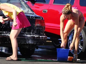 Group of cute girls at a car wash in bikinis and shorts