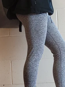 Hot booty and legs in grey sweats closeup, a young candid girl leaning against the wall