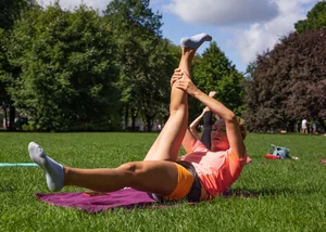 Muscular Girl in Shorts and Socks Doing Yoga in the City Park Candid