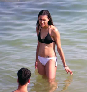 Skinny brunette girl on the beach in black and white bikini