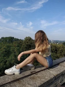 Teen in Sneakers and Denim Shorts Sitting on the Rooftop Candid Photo