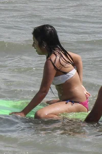 Brunette bikini girl on the beach and surfing in her bikini