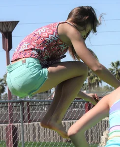Brunette skinny teen in green shorts playing in a bounce house