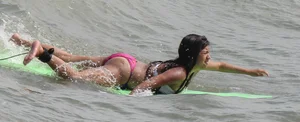 Brunette bikini girl on the beach and surfing in her bikini