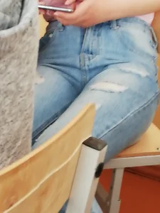 College Girl in Blue High-Waisted Jeans Sitting at the Desk Closeup Photo