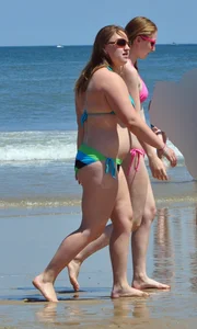 Two beach friends in bikinis one with back dimples and the other thick