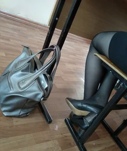 College teen weaking a skirt, black pantyhose and high-heeled shoes sitting at her desk in classroom creepshots