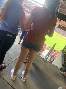 Bunch of girls in various outfits at a Cardinals baseball game