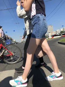 Cute Girl in a Short Denim Skirt Walking on a Street And Waiting on a Crosswalk Gallery