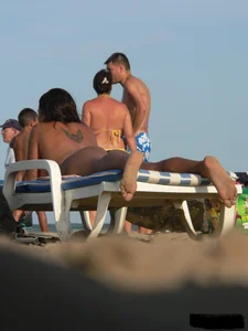 Topless tattooed lady on the beach with fake big tits