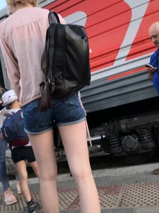 Candid with long thin legs wearing denim shorts waiting to get on a train