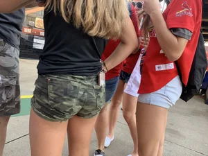 Bunch of girls in various outfits at a Cardinals baseball game