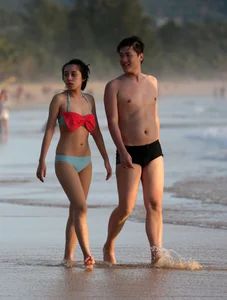 Cute Asian in bikini on the beach with her boyfriend