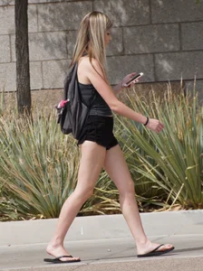 Adorable Girl in Mini Shorts and Slippers Walking Down the Street
