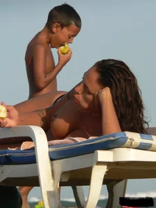 Topless tattooed lady on the beach with fake big tits