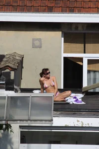 Neighbor on rooftop tanning in bikinis