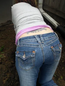 Girl in Jeans With a Tattooed Back Standing Doggy Style on the Floor Ass Closeup