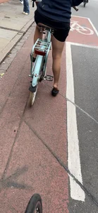 Girl on a bike wearing pantyhose, skirt and flats standing with her shoe half taken off