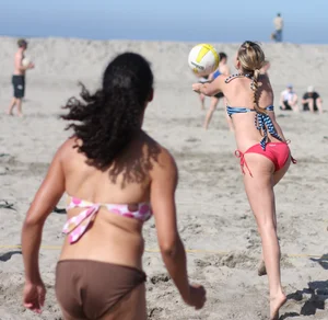 Hot girls playing beach volleyball in bikinis and shorts