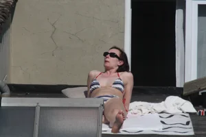 Neighbor on rooftop tanning in bikinis