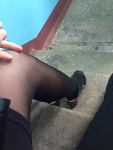 Teen Sitting on the Stairs Step Legs Closeup in Black Pantyhose and Sandals on High Heels