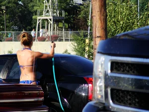 Group of cute girls at a car wash in bikinis and shorts