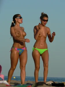 Topless girl on the beach with small boobs wearing a green thong bikini