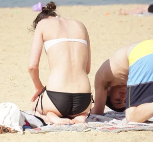 Sexy girl on the beach laying out and bending over in her bikini