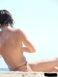 Topless beach milf looking sexy in a tiny g-string bikini