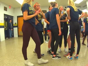 Skinny college teen in leggings bending over a drinking fountain