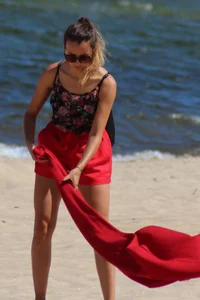 Hottie undressing from her red shorts to her bikini to layout on the beach