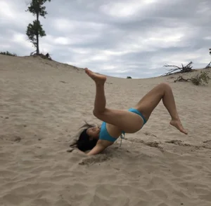 Girl in a Blue Swimsuit Falling After Attempting a Handstand at the Beach