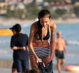 Skinny small boobed girl in a bikini on the beach with her friend